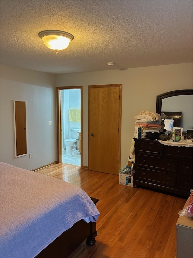 bedroom featuring connected bathroom, a textured ceiling, and wood finished floors
