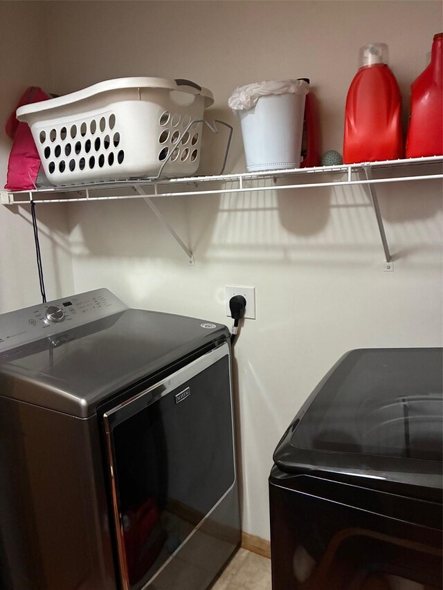 clothes washing area with laundry area, baseboards, and washing machine and dryer