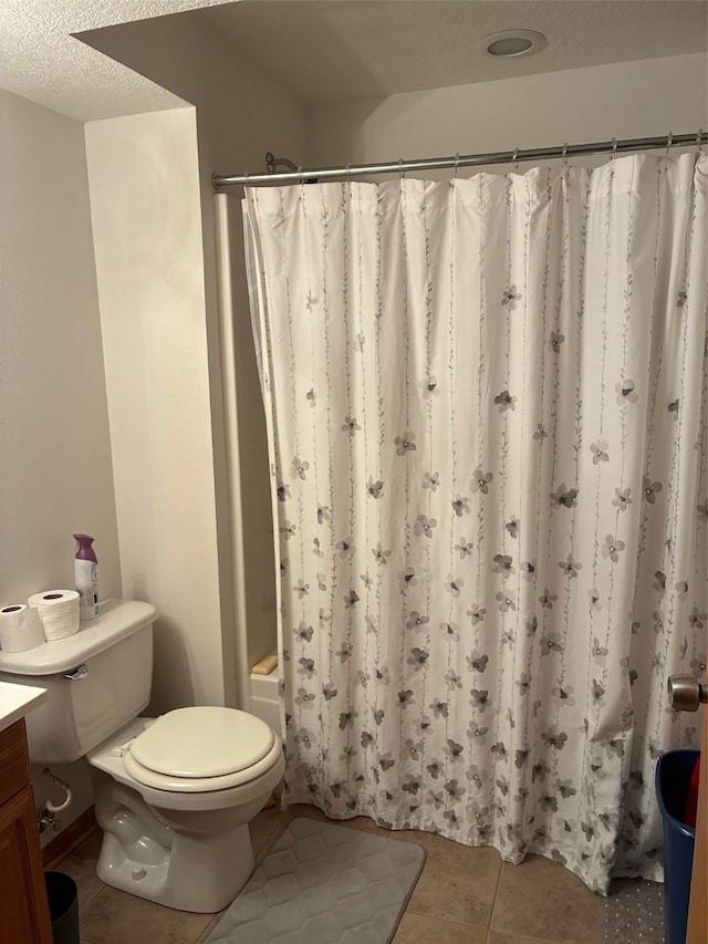 bathroom featuring a textured ceiling, tile patterned flooring, shower / bath combo, vanity, and toilet