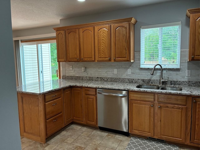 108 S 46th St, West Des Moines, IA 50265 - kitchen with stainless steel dishwasher, a sink, backsplash, brown cabinetry, and a textured ceiling