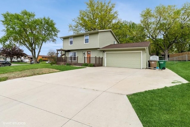 view of front facade with concrete driveway, an attached garage, fence, and a front yard