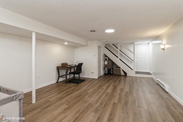 finished below grade area featuring stairs, wood finished floors, baseboards, a baseboard radiator, and recessed lighting