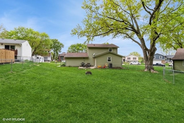 back of property featuring a yard, central AC, and a fenced backyard