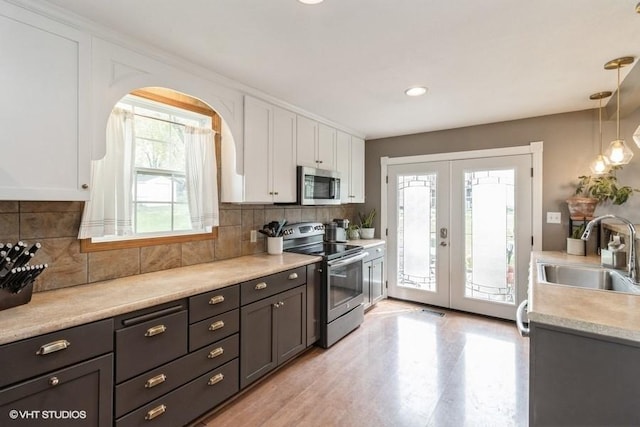 kitchen featuring french doors, a sink, light countertops, stainless steel appliances, and white cabinetry