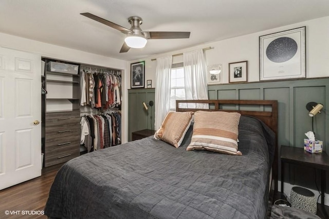 bedroom with a wainscoted wall, a closet, dark wood-style flooring, and a decorative wall