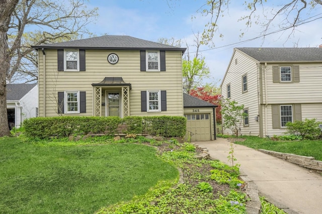 colonial inspired home with a front yard and a detached garage