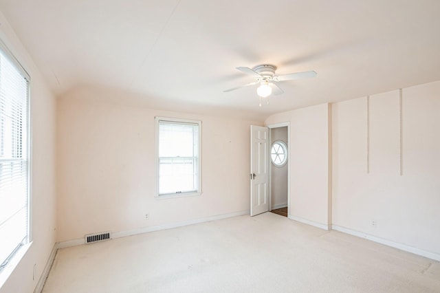 empty room featuring ceiling fan, visible vents, light carpet, and baseboards