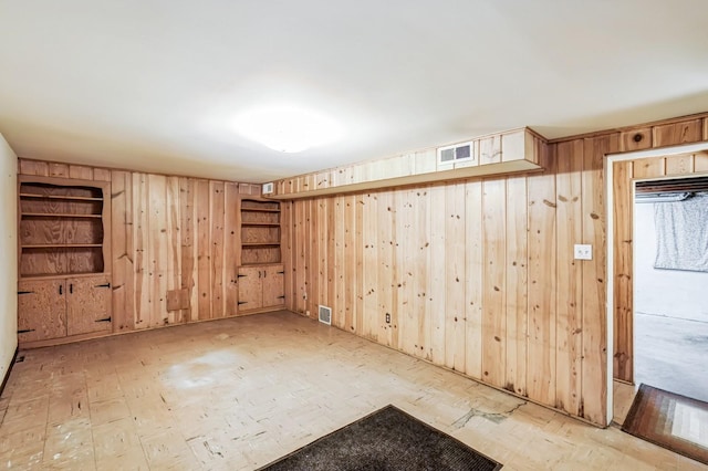 empty room featuring wood walls and visible vents