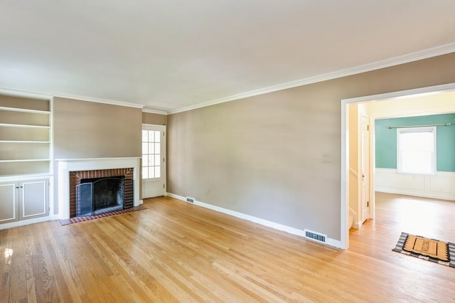 348 49th St, Des Moines, IA 50312 - unfurnished living room featuring ornamental molding, light wood finished floors, healthy amount of natural light, and a fireplace