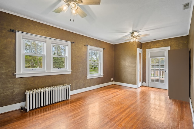 unfurnished room featuring wood-type flooring, ceiling fan, radiator heating unit, and a healthy amount of sunlight