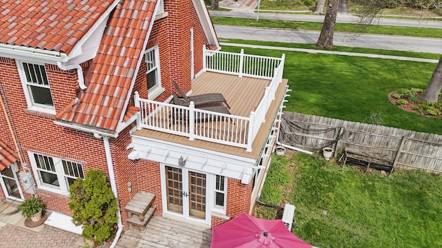 exterior space featuring brick siding, fence, a tile roof, and a balcony