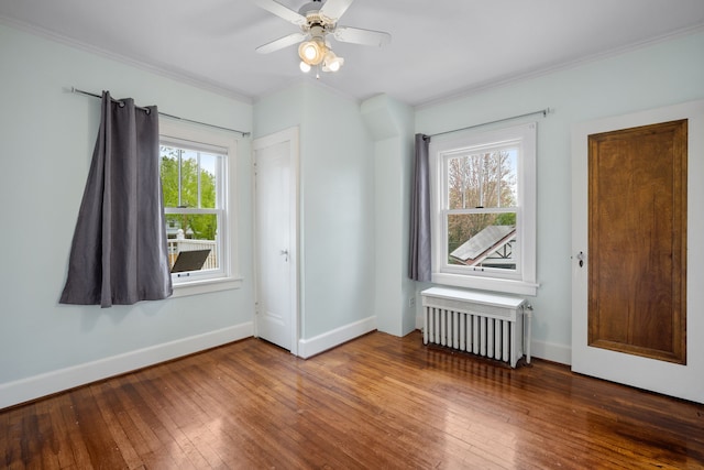spare room with ceiling fan, crown molding, hardwood / wood-style flooring, baseboards, and radiator