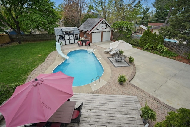 view of swimming pool with a water slide, a fenced backyard, a patio area, an outdoor structure, and a yard
