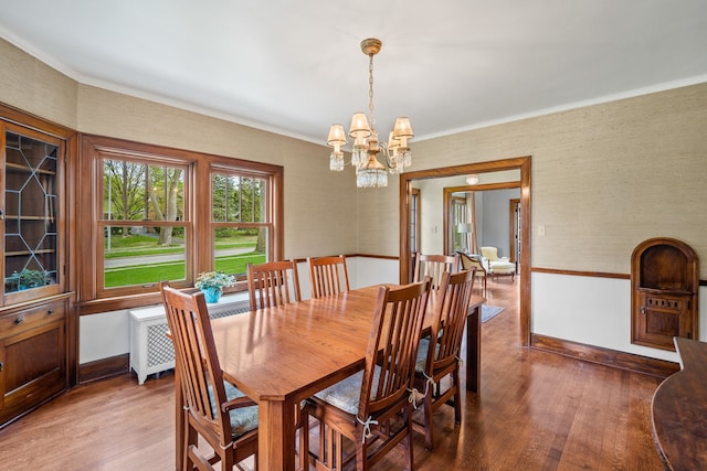 dining area featuring crown molding, wood finished floors, and a notable chandelier