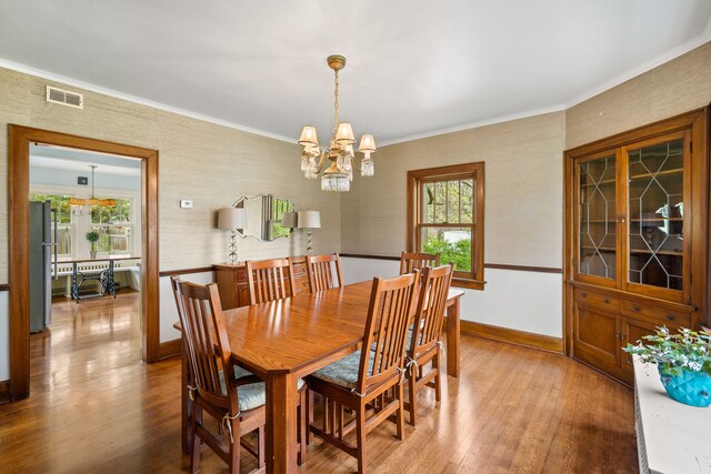 dining space featuring visible vents, ornamental molding, wood finished floors, and a chandelier