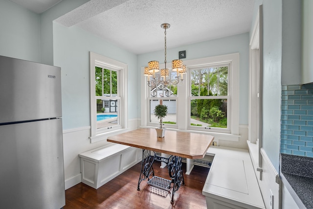 dining area featuring dark wood-style flooring, wainscoting, breakfast area, a textured ceiling, and a chandelier