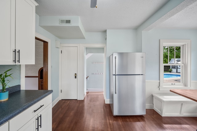 kitchen featuring freestanding refrigerator, dark wood-style flooring, white cabinetry, and visible vents