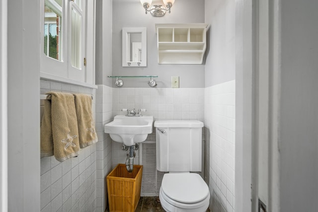 half bathroom featuring wainscoting, toilet, and tile walls