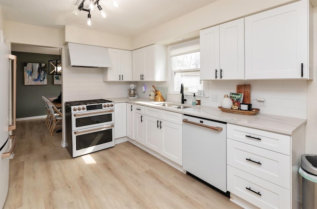 kitchen featuring decorative backsplash, premium range hood, range with two ovens, a sink, and dishwasher
