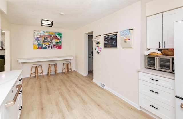 interior space featuring light wood-style floors, baseboards, and a toaster