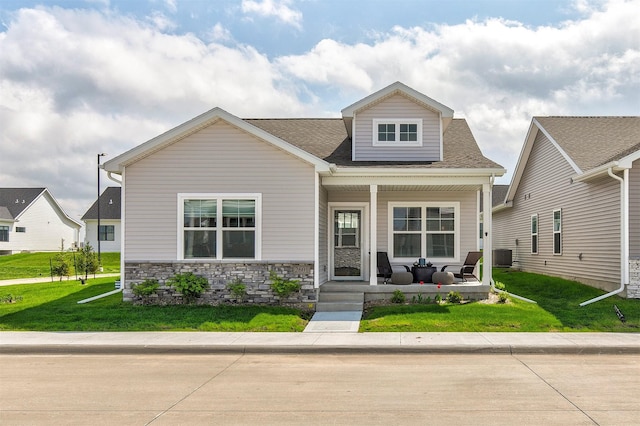 2601 NW 30th Ln, Ankeny, IA 50023 - craftsman-style home with a porch, cooling unit, a front lawn, a shingled roof, and stone siding