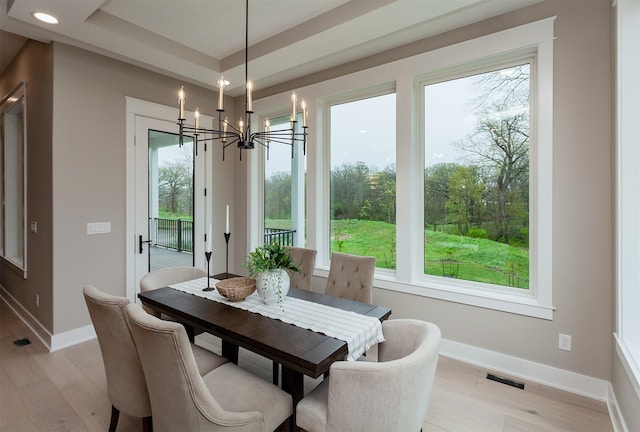 dining area featuring light wood-type flooring, baseboards, and a chandelier