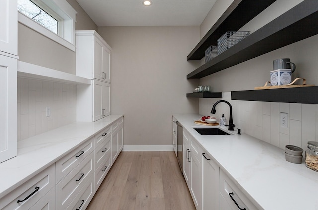 interior space with a sink, light wood finished floors, recessed lighting, baseboards, and decorative backsplash