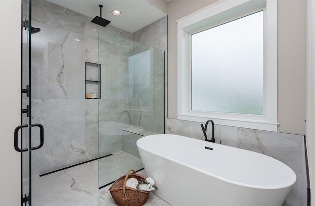 full bathroom with a marble finish shower, a soaking tub, and tile walls