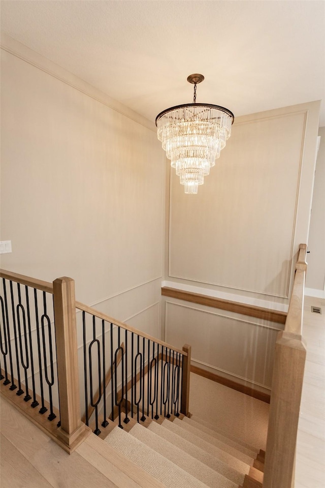 stairs with an inviting chandelier and crown molding