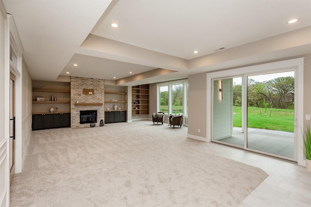 unfurnished living room featuring light colored carpet, a fireplace, built in shelves, baseboards, and recessed lighting