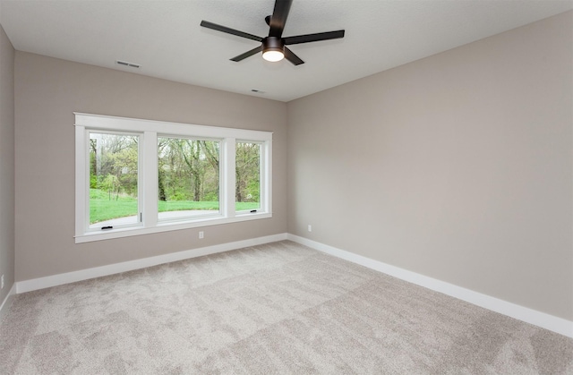 carpeted empty room with baseboards, visible vents, and ceiling fan