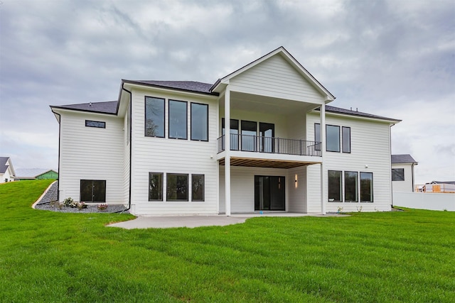 rear view of property featuring a lawn, a patio, and a balcony