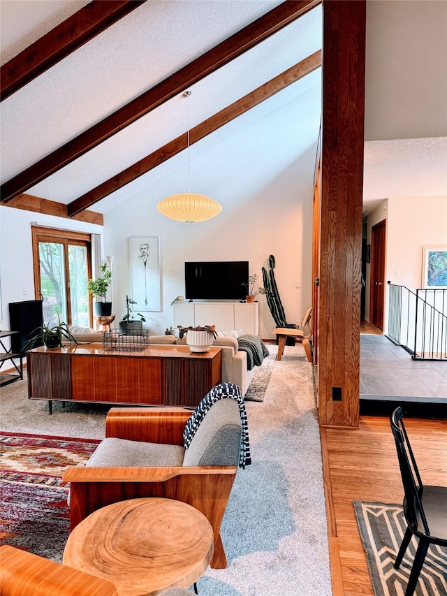 living area featuring a healthy amount of sunlight, high vaulted ceiling, beamed ceiling, and wood finished floors