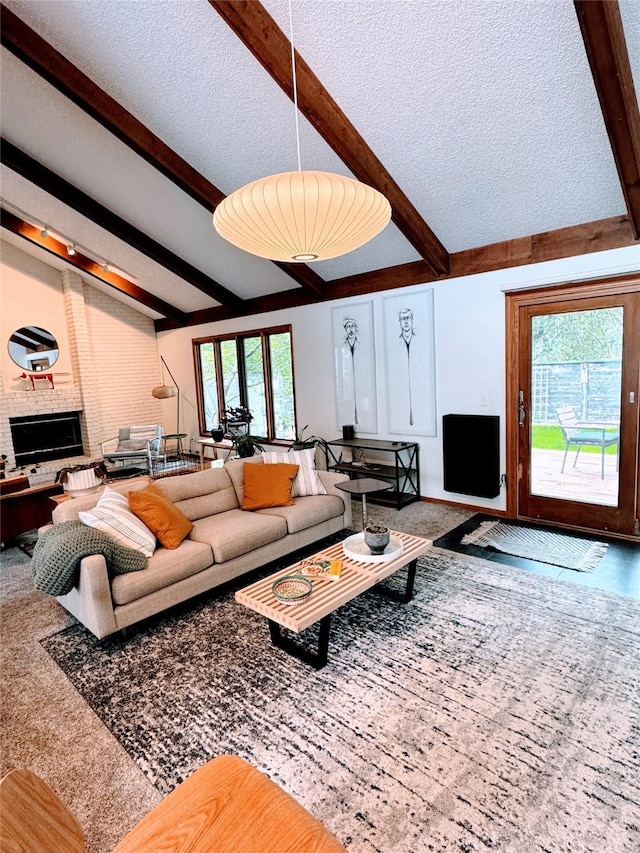 living room featuring vaulted ceiling with beams, a brick fireplace, and a textured ceiling