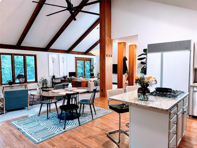 dining room featuring light wood-style floors, ceiling fan, beam ceiling, and high vaulted ceiling