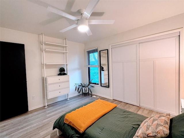 bedroom featuring light wood-type flooring, a ceiling fan, baseboards, and a closet