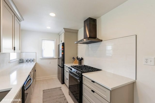 kitchen featuring baseboards, decorative backsplash, black appliances, and wall chimney range hood
