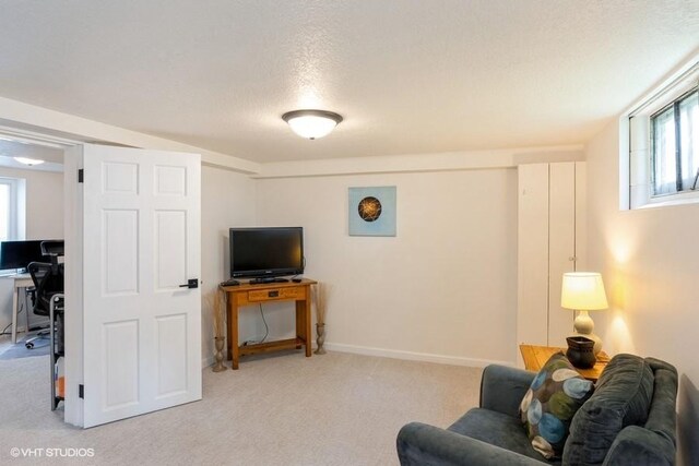 living area with light carpet and a textured ceiling