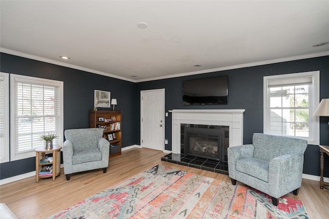 living area with baseboards, ornamental molding, wood finished floors, and a tile fireplace
