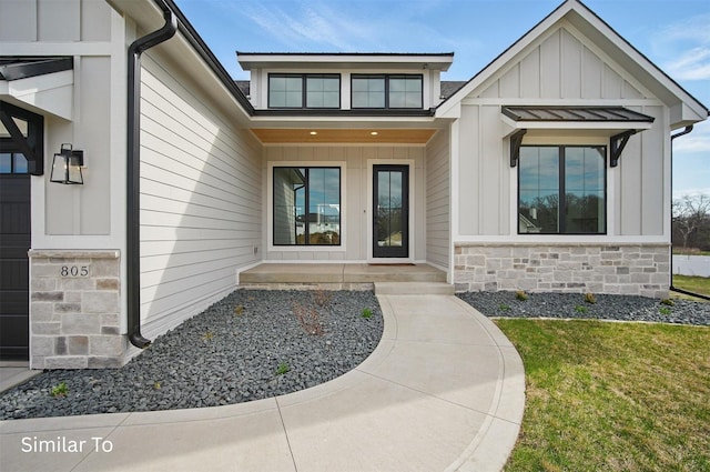 7325 NW Beaver Dr, Johnston, IA 50131 - property entrance featuring a lawn, board and batten siding, and stone siding