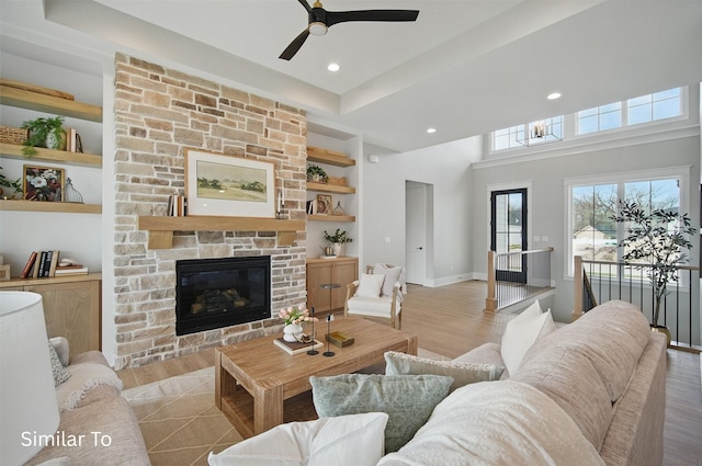 7325 NW Beaver Dr, Johnston, IA 50131 - living area with built in features, baseboards, a stone fireplace, ceiling fan, and light wood-type flooring