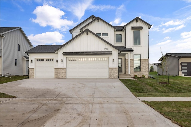 modern farmhouse featuring a front lawn, stone siding, board and batten siding, concrete driveway, and an attached garage