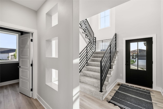 entryway with light wood-style floors, baseboards, and stairs