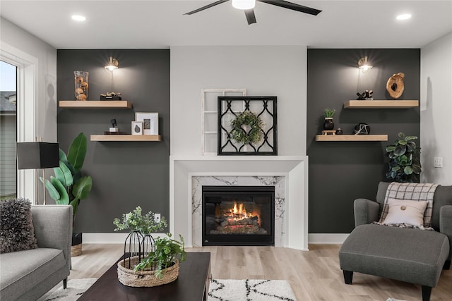 living area with ceiling fan, wood finished floors, and a fireplace
