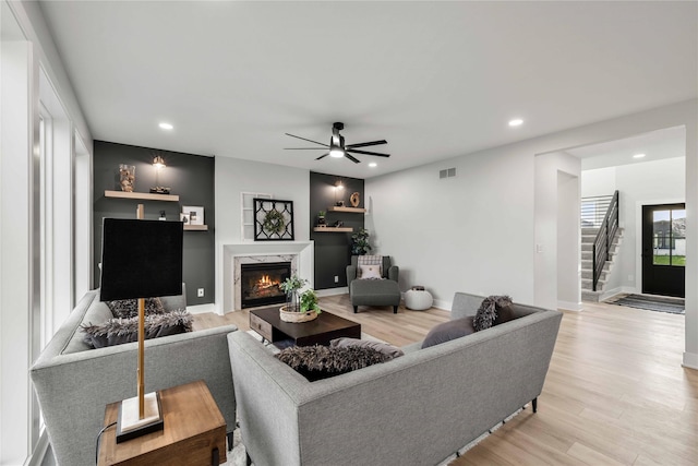 living area with a high end fireplace, recessed lighting, ceiling fan, and light wood finished floors