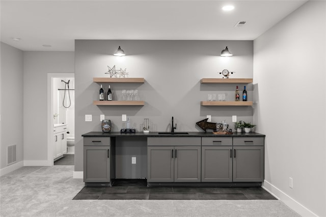 bar featuring baseboards, wet bar, visible vents, and a sink