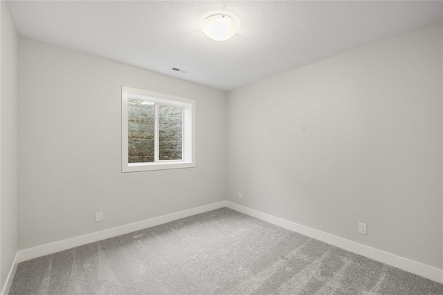 carpeted spare room featuring a textured ceiling, baseboards, and visible vents