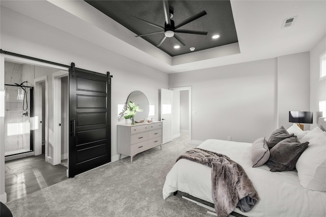 bedroom with a ceiling fan, visible vents, a barn door, a tray ceiling, and recessed lighting