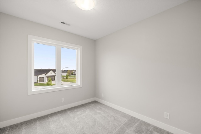 spare room with baseboards, visible vents, and light carpet