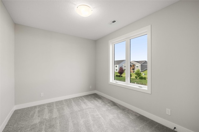 carpeted empty room featuring visible vents and baseboards